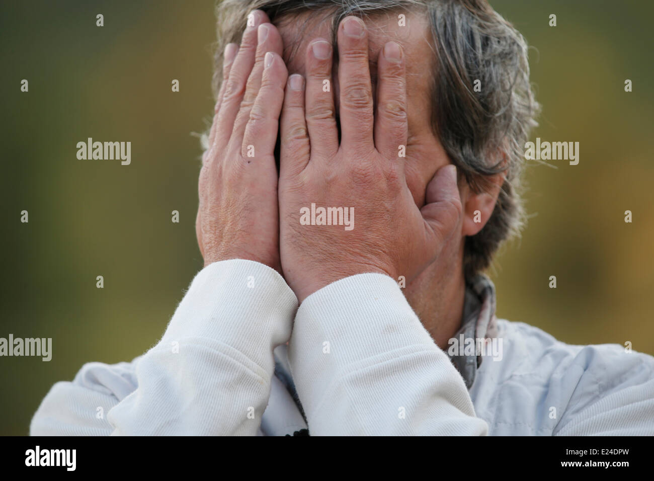 Mann versteckt sein Gesicht mit den Händen. Stockfoto