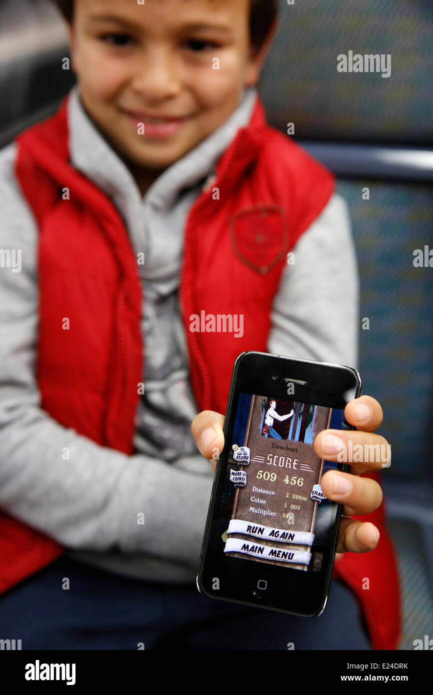 8-Year-Old Boy zeigt ein Spielstand auf einem Telefon Stockfoto