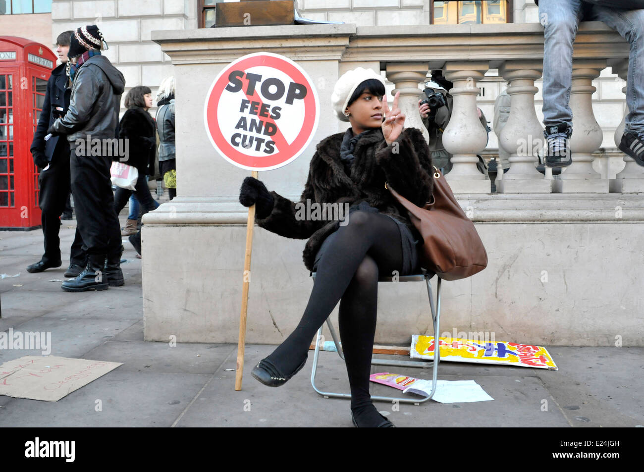 Eine Studentin Demonstrant sitzend, hält einen Banner lesen "Stop Gebühren und Kürzungen", London, England Stockfoto