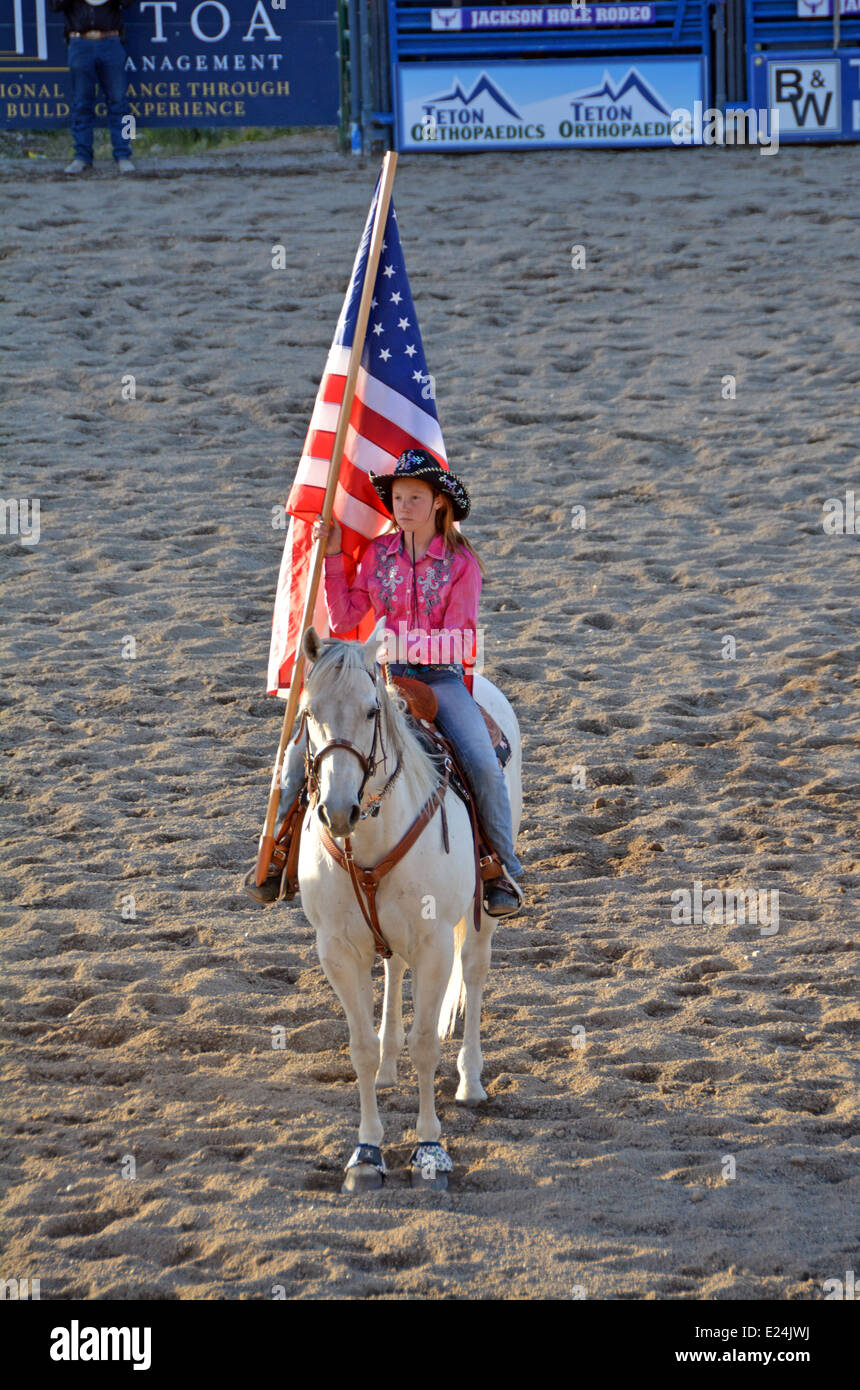 11 Jahre altes Mädchen auf einem Pferd trägt die Flagge bei der Eröffnung des Jackson Hole Rodeo. Stockfoto