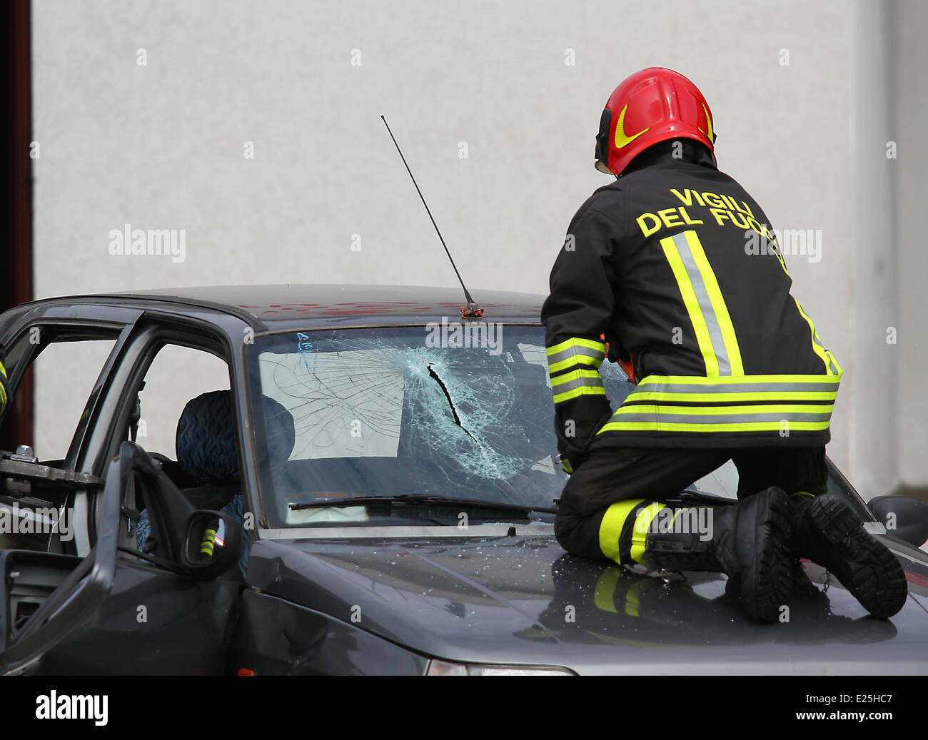 Italienische Feuerwehrmann während bricht das Glas Windschutzscheibe kaputtes Auto um die Verletzten zu retten Stockfoto