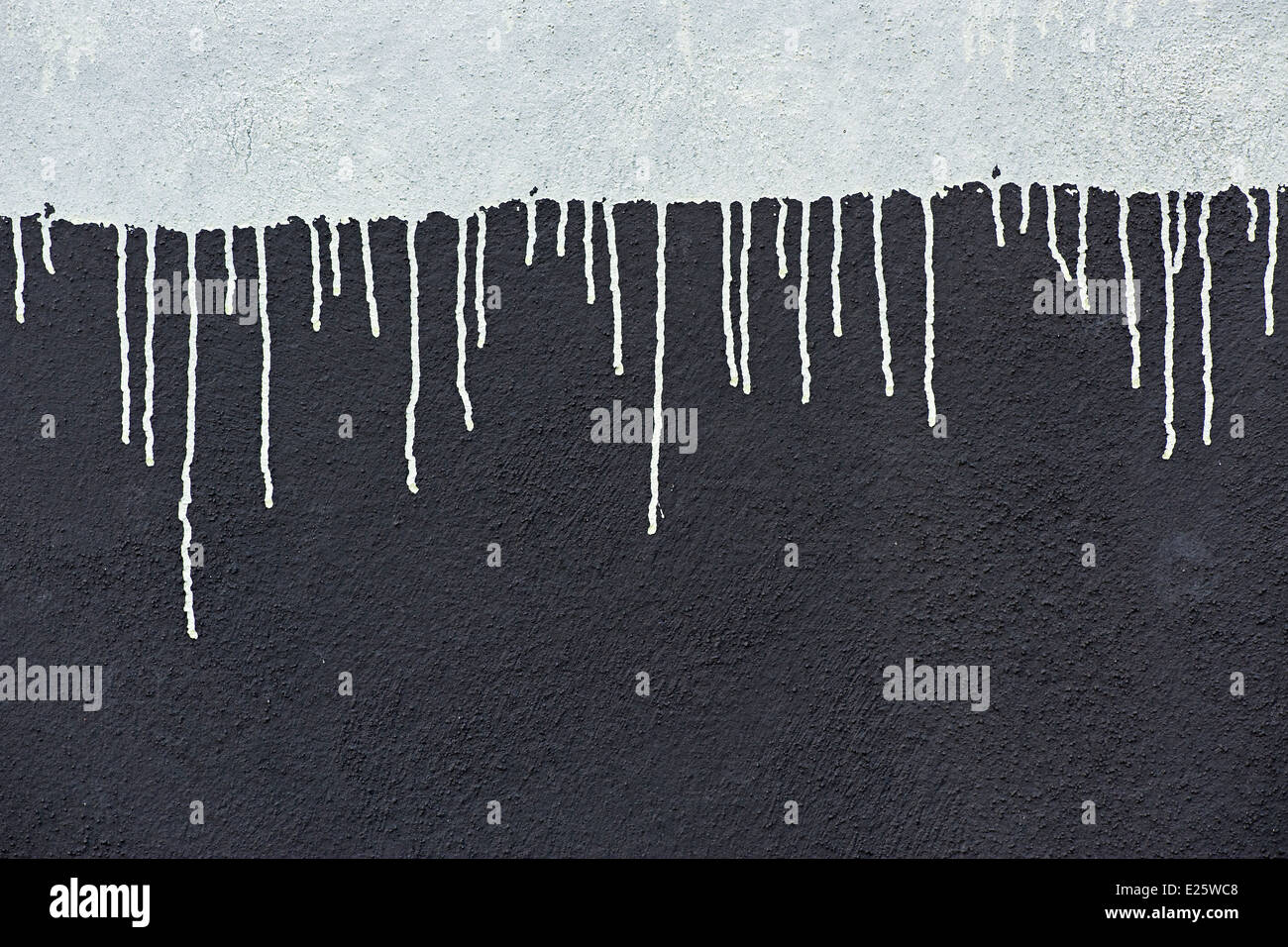 Grauer Farbe fällt auf eine dunkle graue Wand Stockfoto