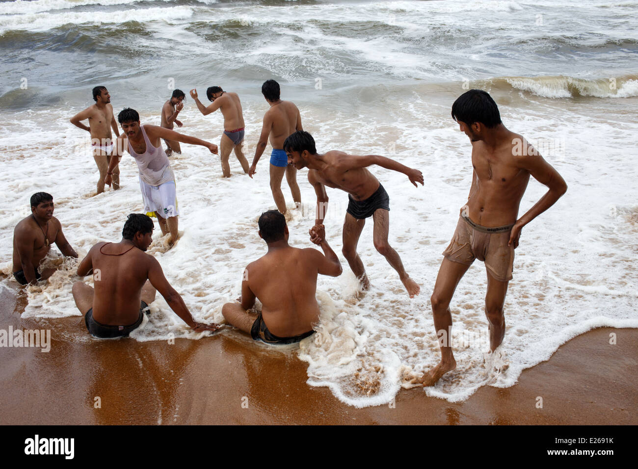 Eine Gruppe von betrunkenen indische Männer spielen im Wasser am Strand in Calangute, Goa, Indien. Stockfoto