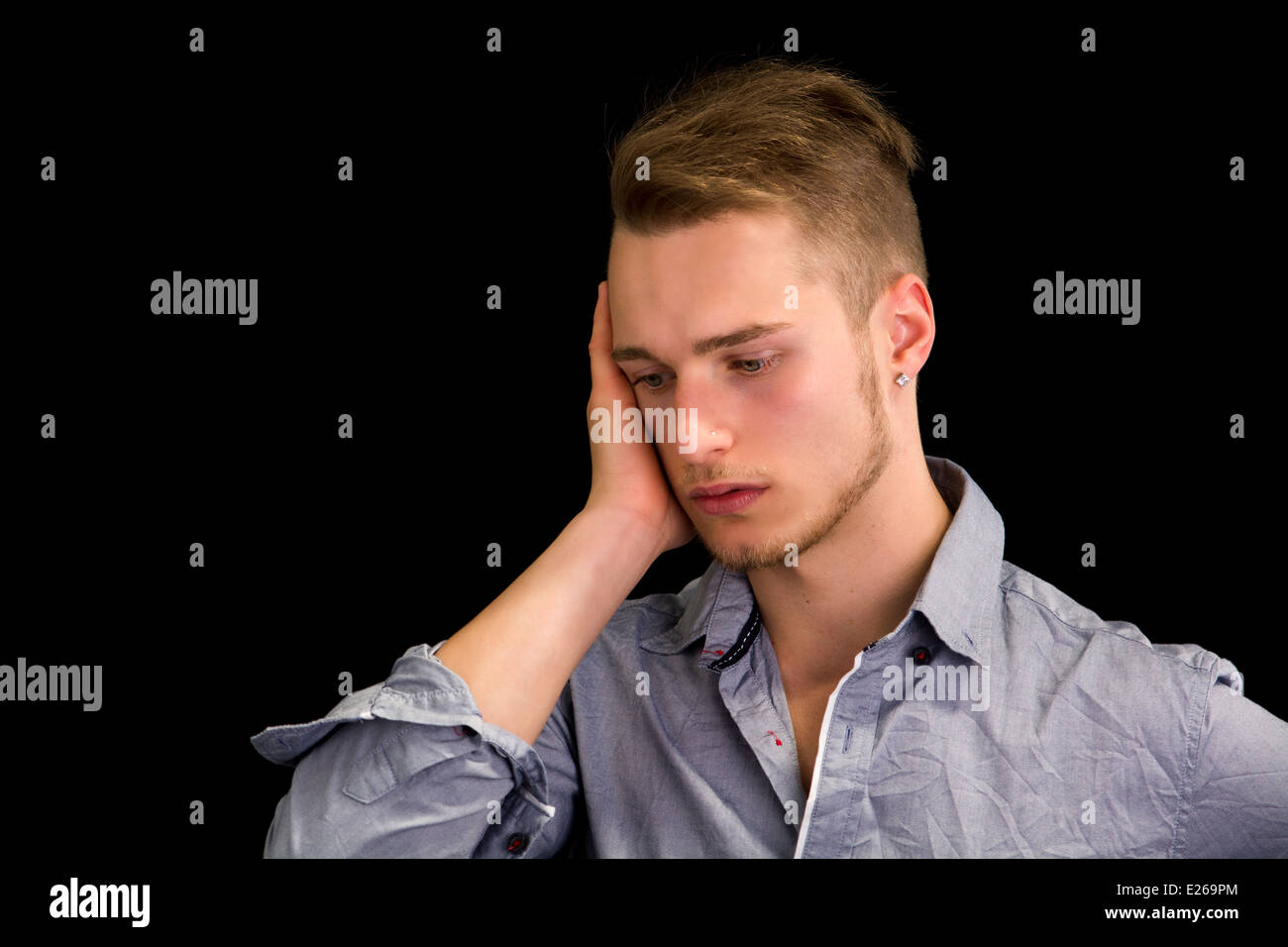 Traurig oder beunruhigt hübscher junger Mann blickte, isoliert auf schwarz Stockfoto