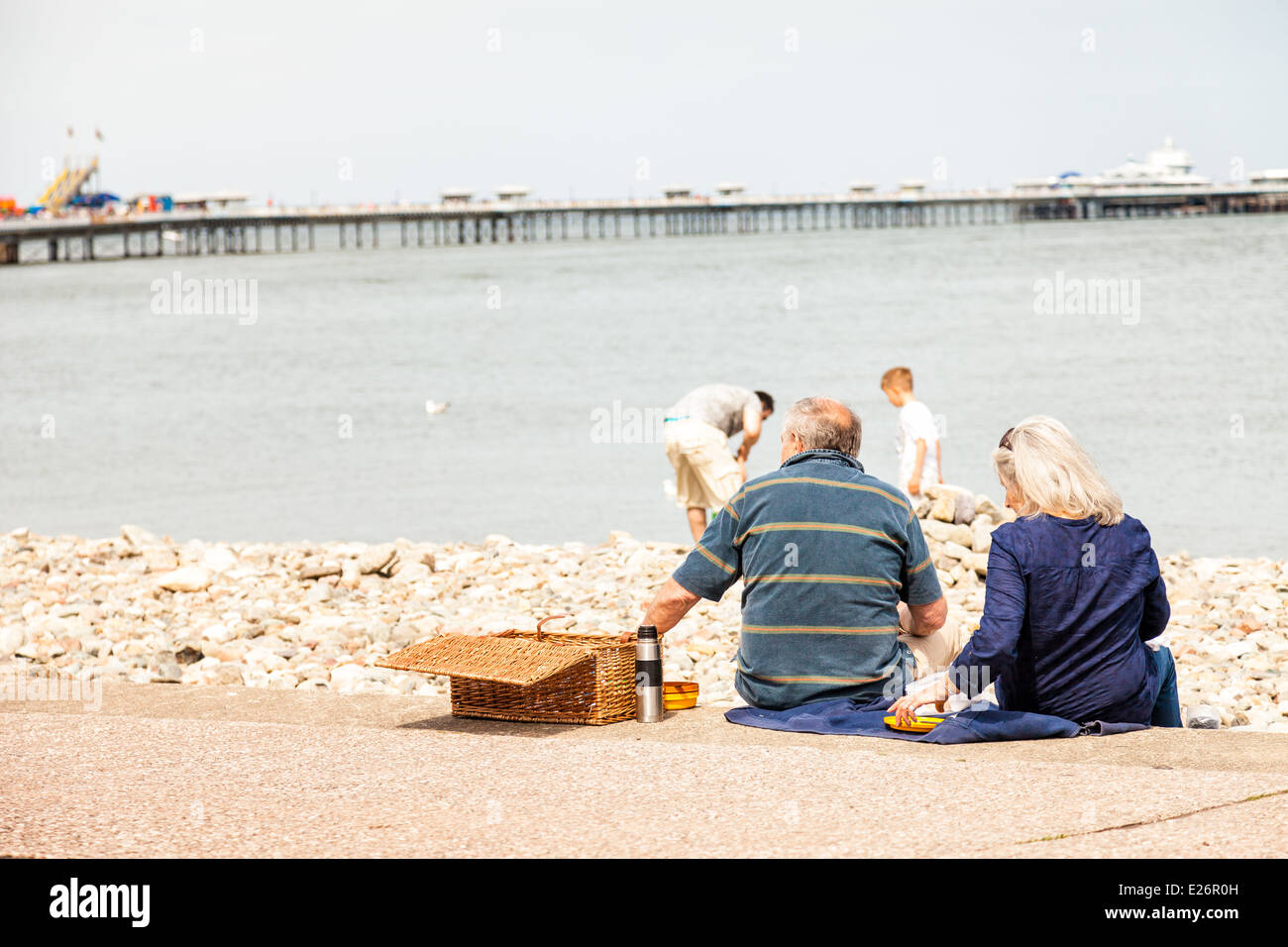 Älteres Paar mit Picknick auf Llandudno promenade Schritte, genießen den Blick aufs Meer Stockfoto