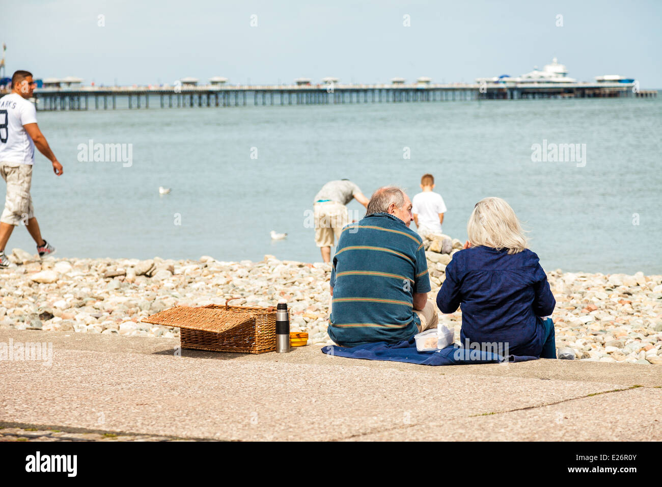Älteres Paar mit Picknick auf Llandudno promenade Schritte, genießen den Blick aufs Meer Stockfoto