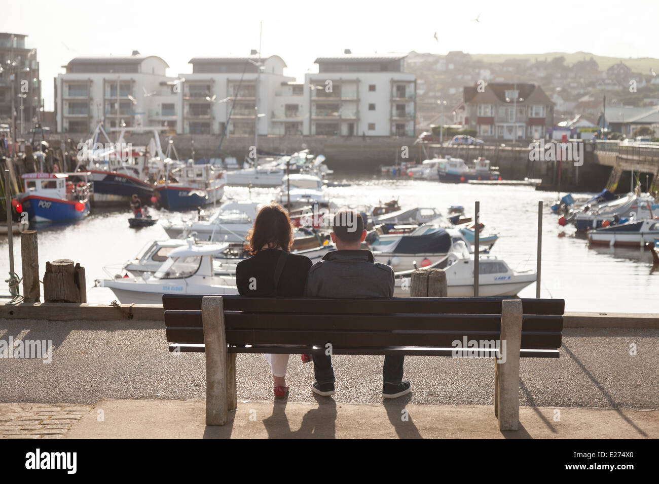 Paar auf einer Bank sitzend, West Bay, Bridport Harbour, Dorset England UK Stockfoto