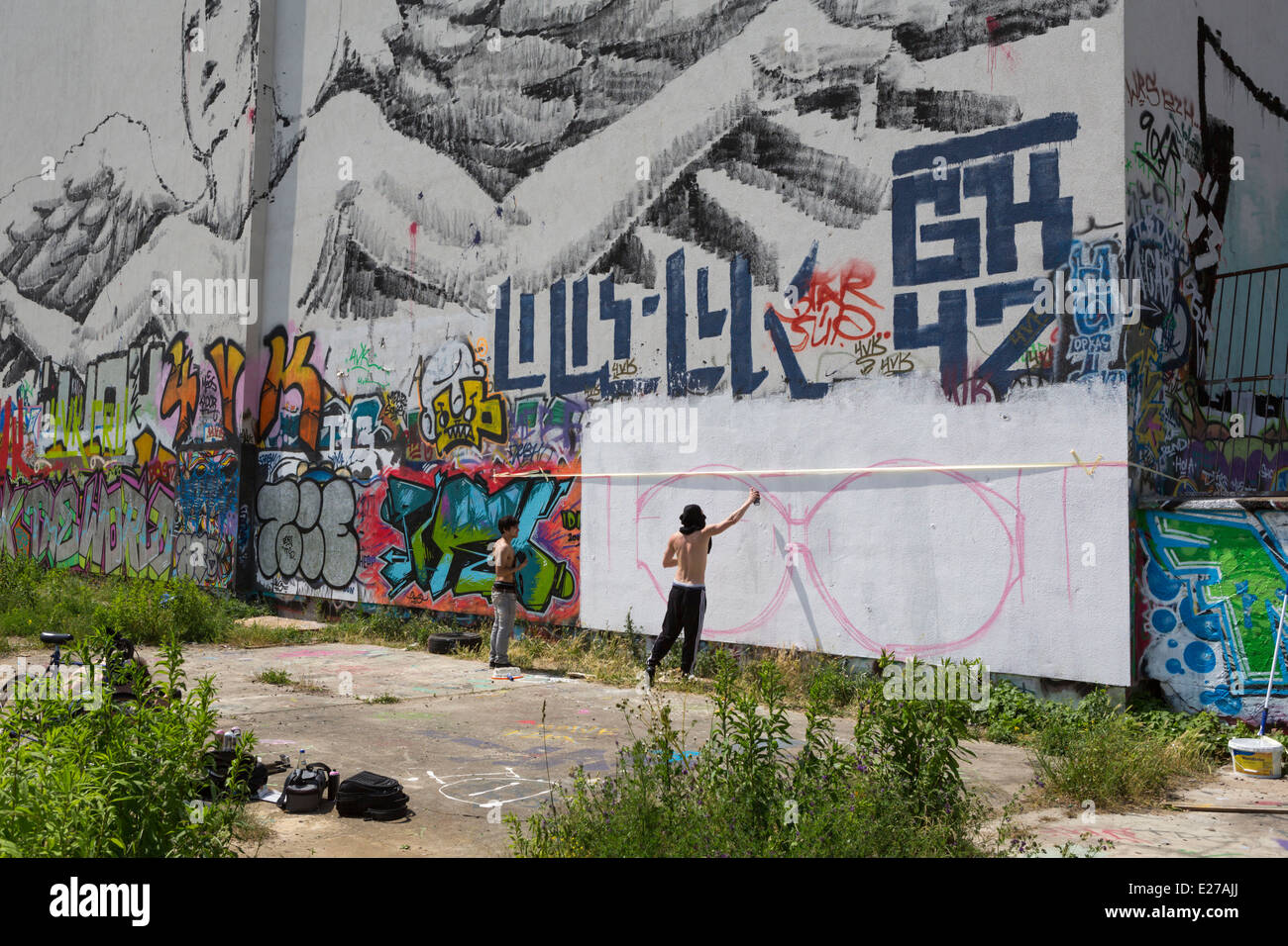 Junge Hausbesetzer Sprühen von Graffiti auf eine Mauer in Friedrichshain, einem Teil von Berlin, Deutschland Stockfoto
