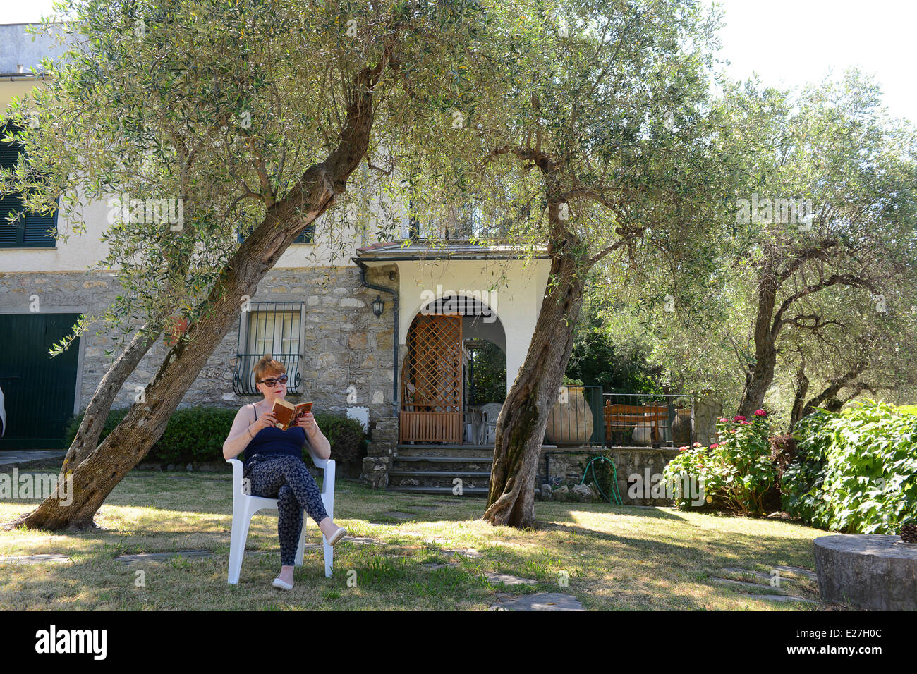 Frau entspannen Lesung im Garten zu Hause Ferienvilla in Chiavari Italien / Urlaub Europäische weiße Kaukasische Frau Stockfoto