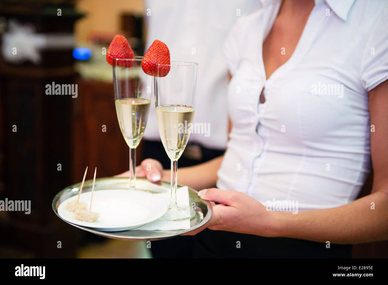 Kellnerin, Champagner mit Erdbeeren und Brot mit Salz auf einem Tablett  serviert Stockfotografie - Alamy