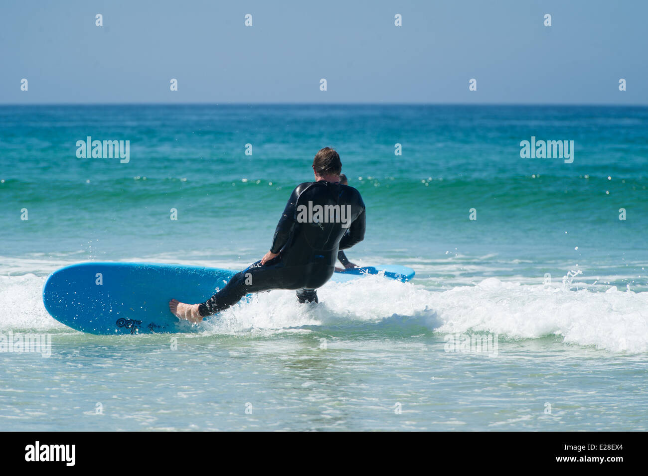 Ein Surfer in St. Ives, Cornwall, England, aus ihrem Surfbrett fallen. Stockfoto