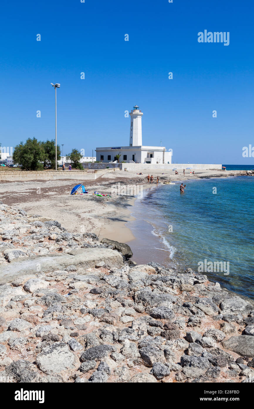 Weißer Leuchtturm gegen blauen Himmel mit felsigen Strand an einer Bucht in der Region San Cataldo, Apulien, Salento, Süditalien Stockfoto