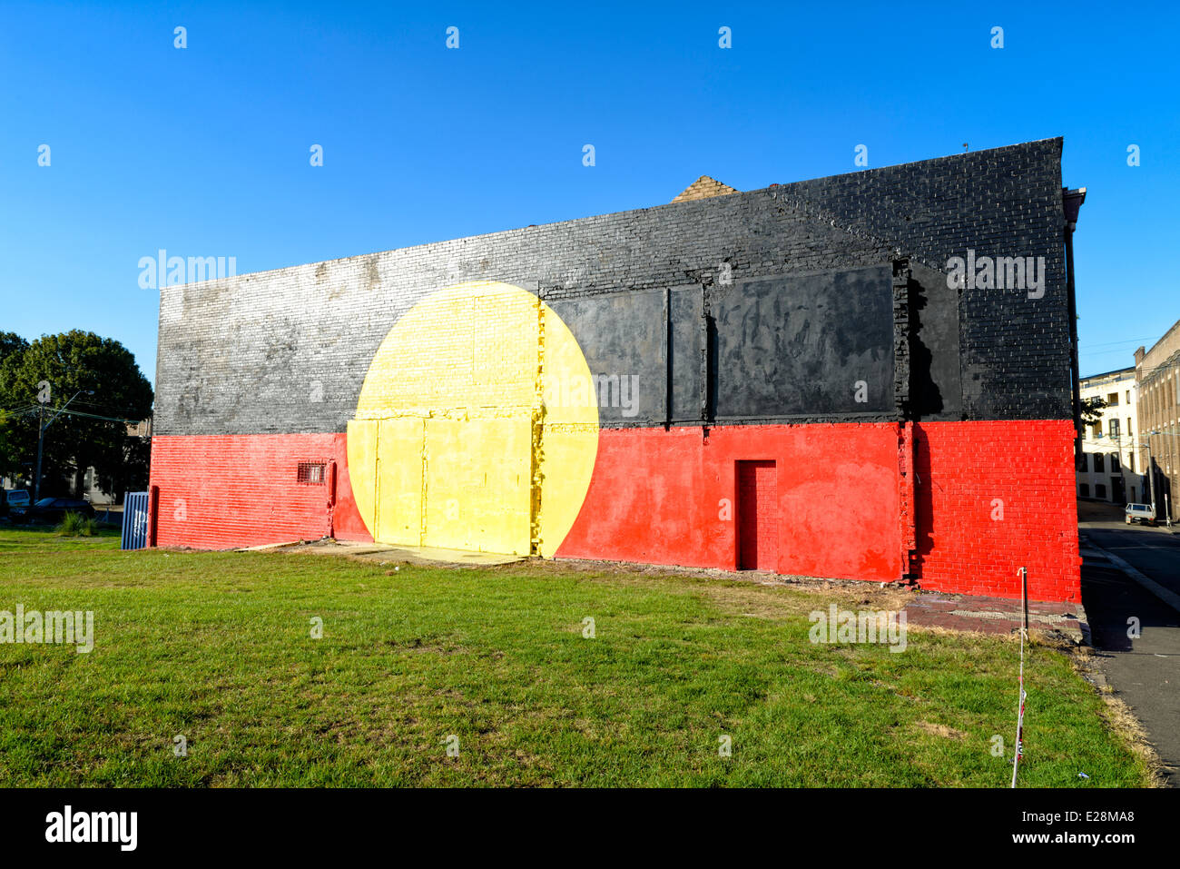 Aboriginal Flagge Wandbild gemalt in leuchtenden Farben auf der Seite eines Gebäudes in Redfern, Sydney, Australien. Rechte der indigenen Bevölkerung, Protest; Aborigine-Flagge. Stockfoto