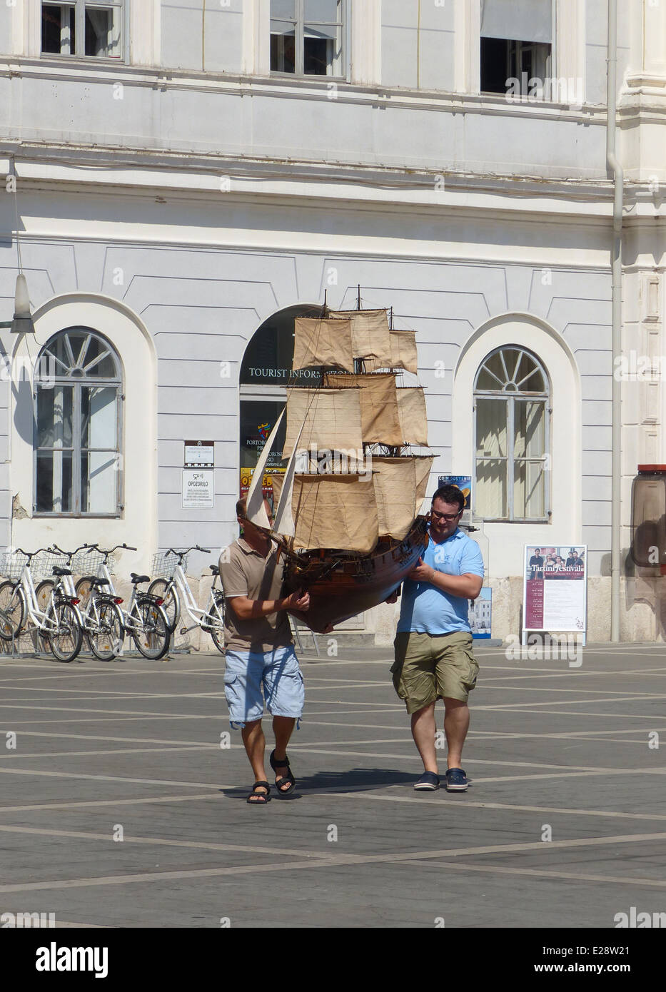 Zwei Männer tragen ein großes Modell Schiff über einen Marktplatz Stockfoto