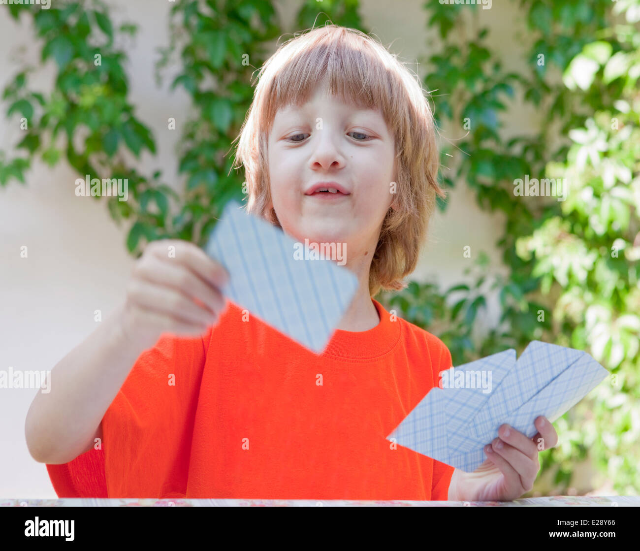 Junge mit blonden Haaren Spielkarten im freien Stockfoto