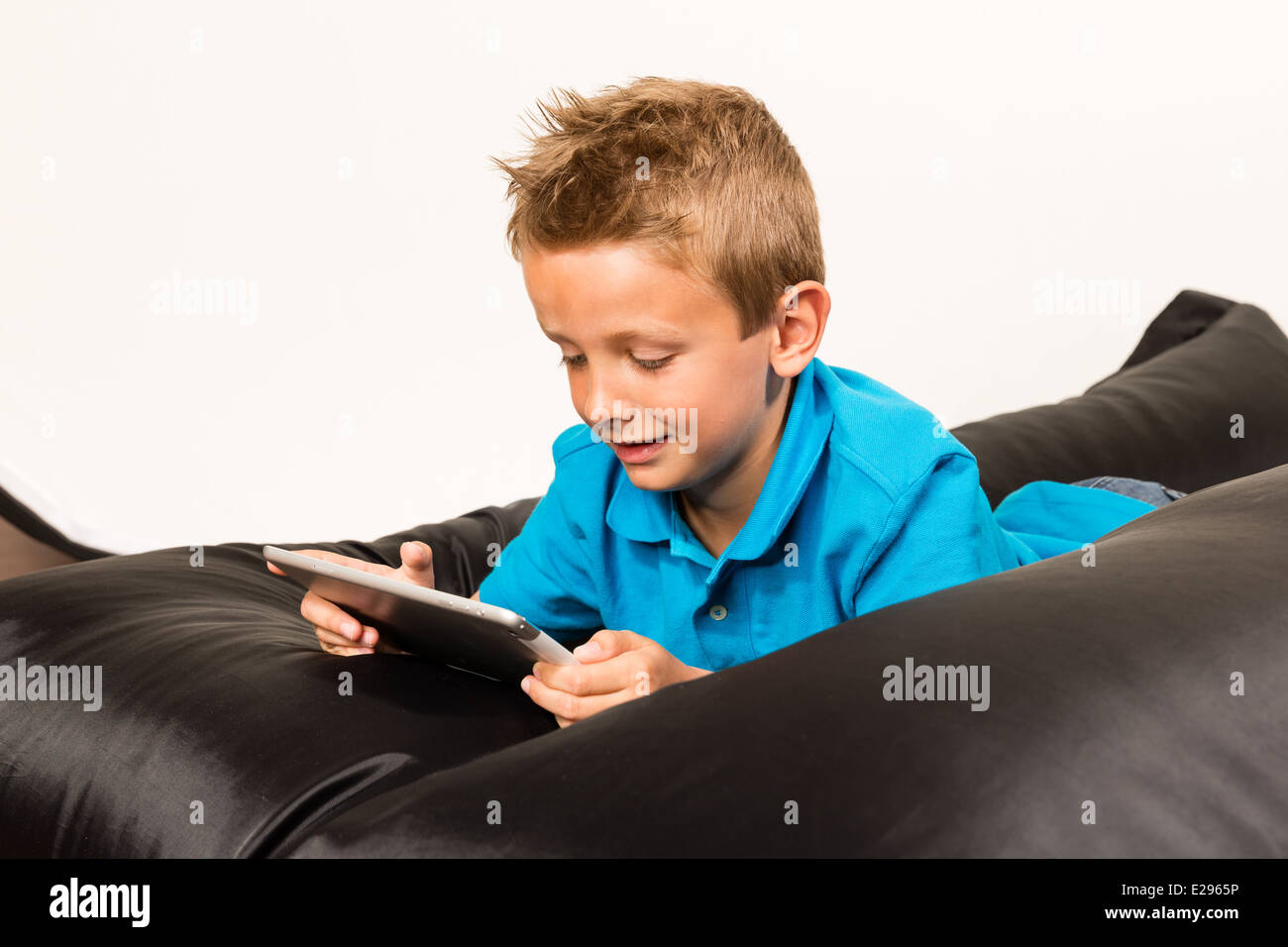 Junge liegend auf Sitzsack mit seinem Tablet. Studio auf weißem Hintergrund gedreht. Stockfoto