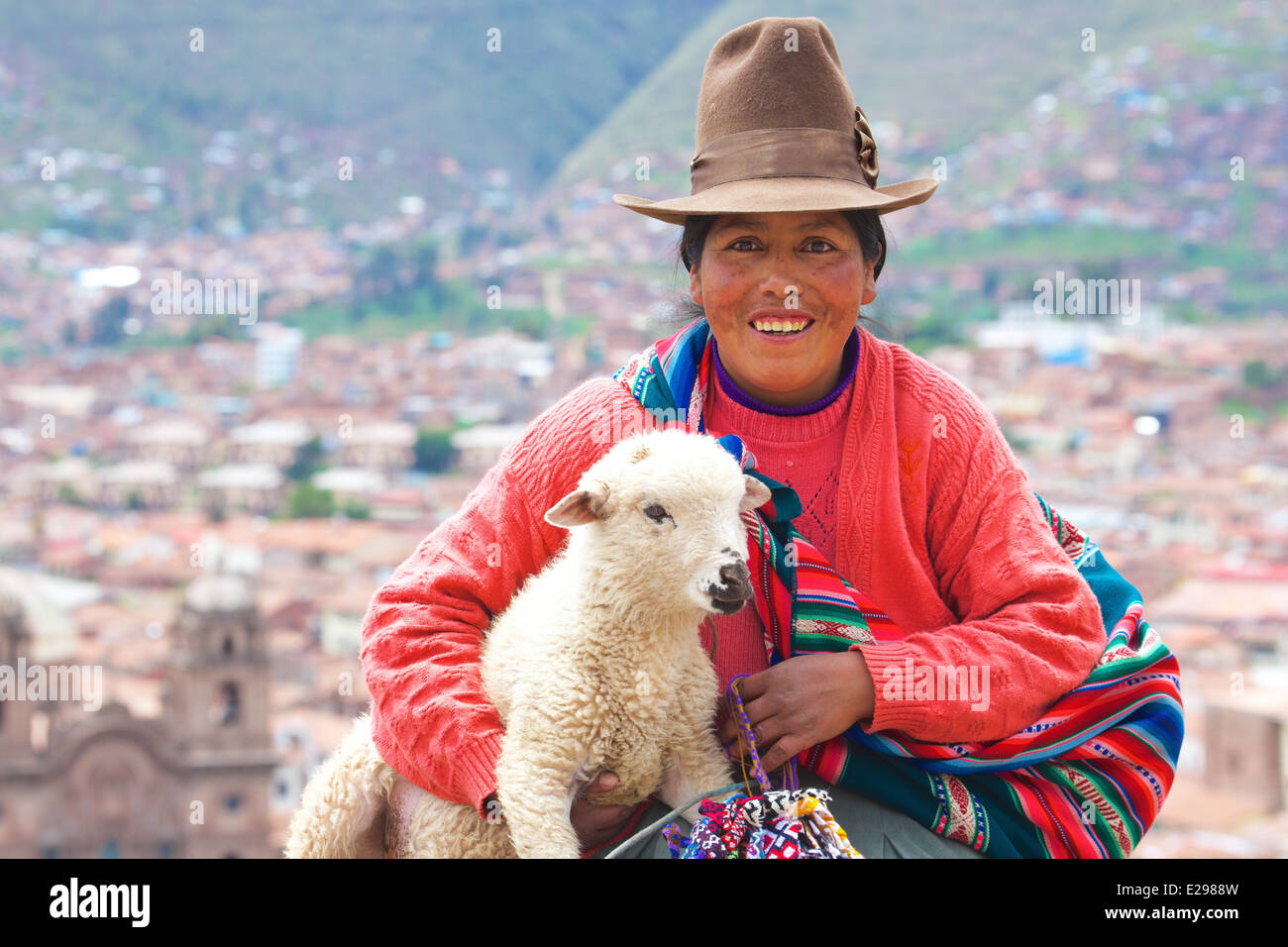 Ein Porträt einer Quechua-Frau in einheimischen Trachten hält ein Lamm in Cusco in den Anden, Peru, Südamerika Stockfoto