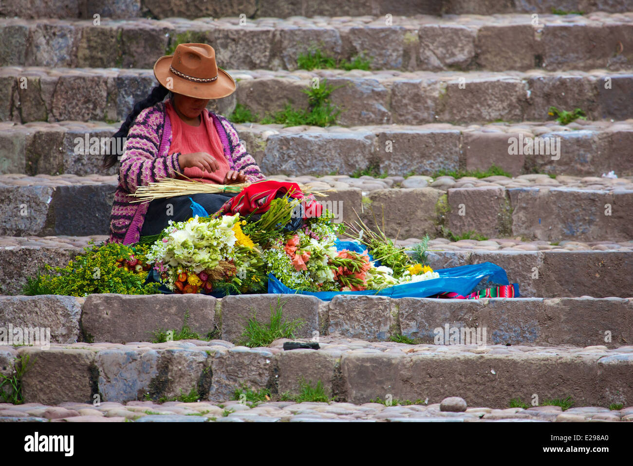 Eine Quechua-Frau in einheimischen Trachten verkauft Blumen auf steinernen Stufen in Cusco, die Anden, Peru, Südamerika Stockfoto Eine Quechua-Frau in einheimischen Trachten verkauft Blumen auf steinernen Stufen in Cusco, die Anden, Peru, Südamerika Stockfoto