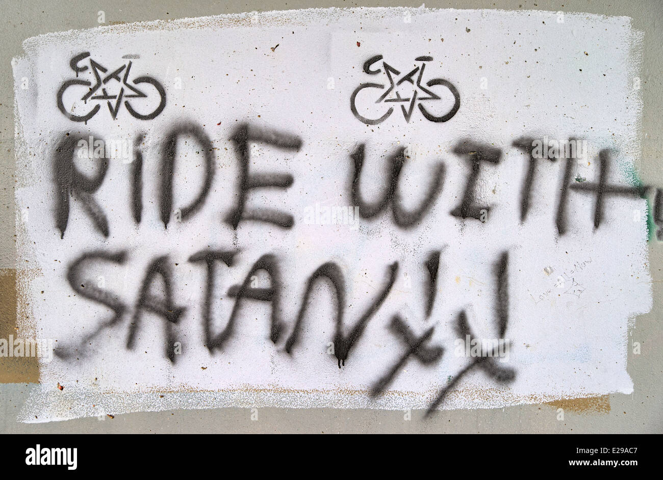 Ein spritzlackiert Graffiti Schild mit der Aufschrift Fahrt mit Satan mit Symbolen auf eine Betonwand. Stockfoto