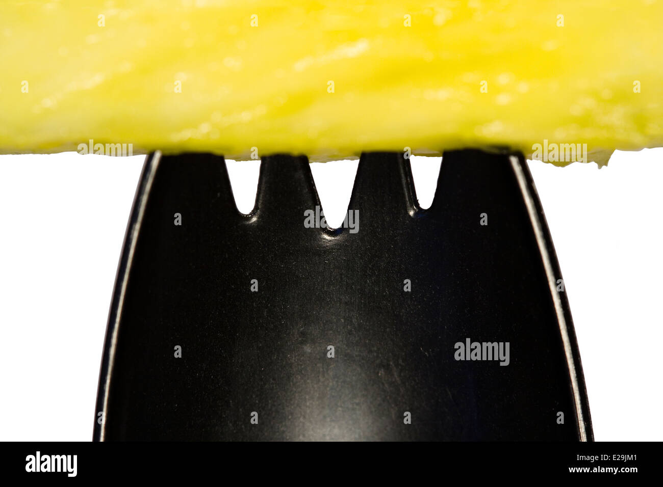 Schneiden Sie aus. Gelbe Ananas Stück auf einem schwarzen Kunststoff Spork auf weißem Hintergrund Stockfoto