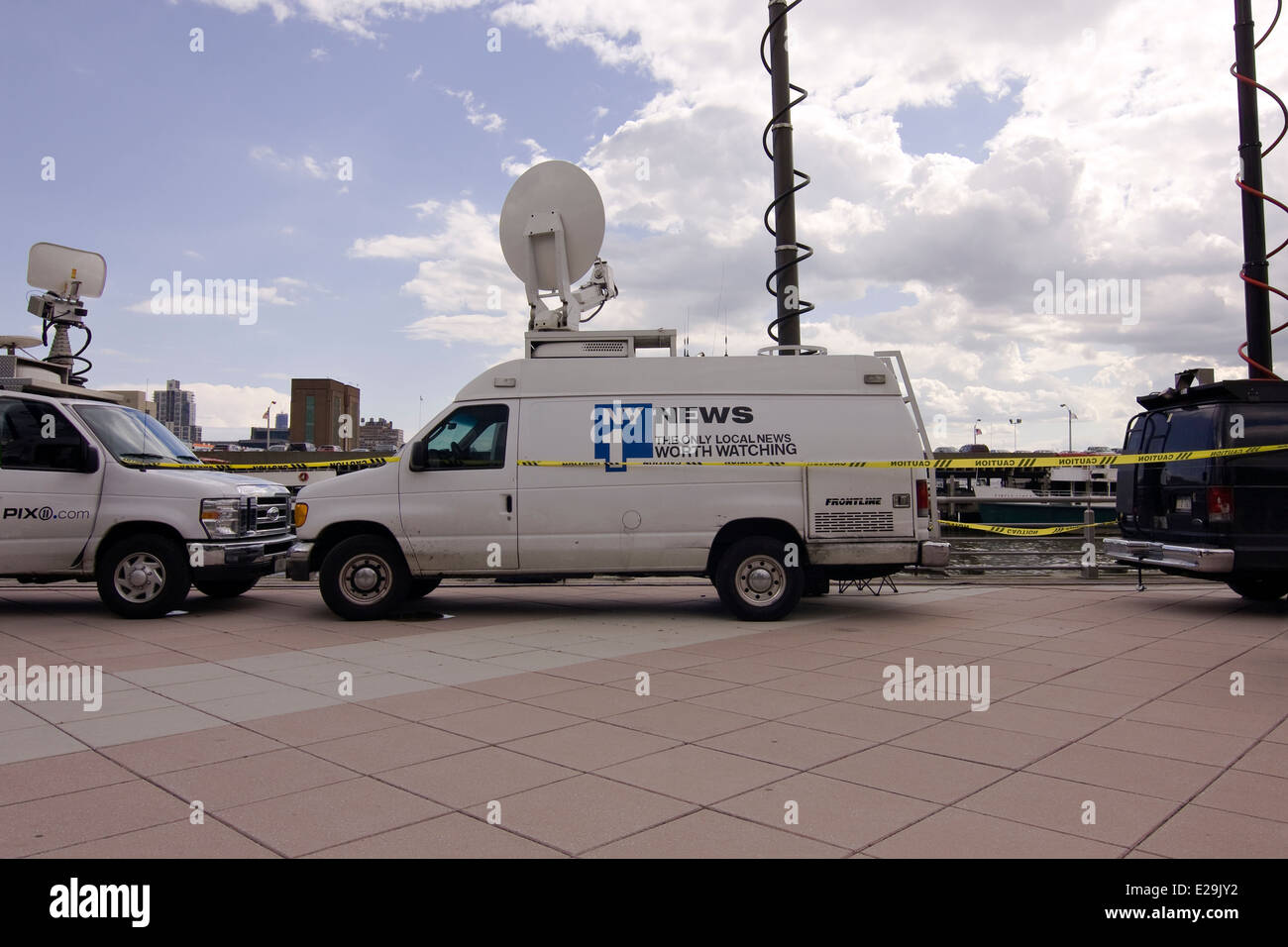 Weiße NY1 Live News Mobile Einheit Van umgeben von Absperrband und parkte neben anderen Live Mobile News Vans Stockfoto