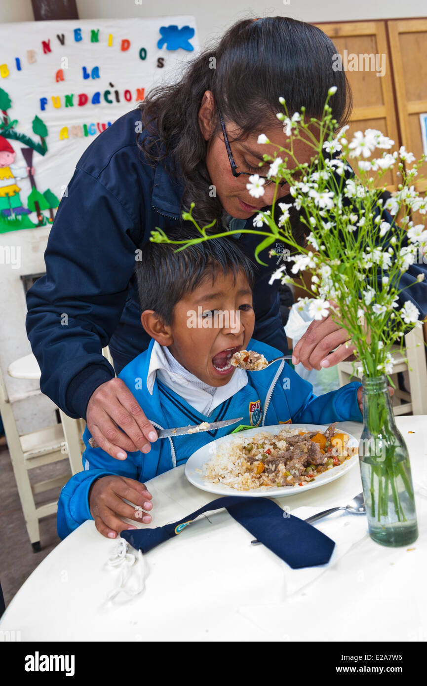 Peru, Cuzco Provinz, Cuzco, Erzieher und Kind mit Mittagessen in einem der Restaurants von Ninos Unidos Peruanos gemeinnützige Stockfoto
