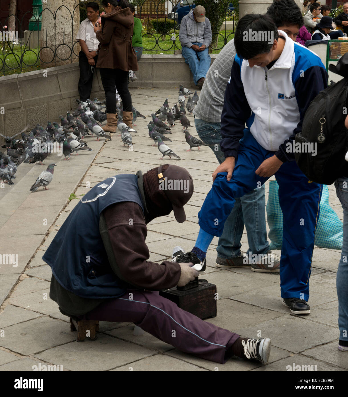 Mann hat seine Schuhe von einem maskierten Schuh sauberer poliert. Maskierte, weil er einen niedrigen Job spürt, daß er will keine Anerkennung. Stockfoto