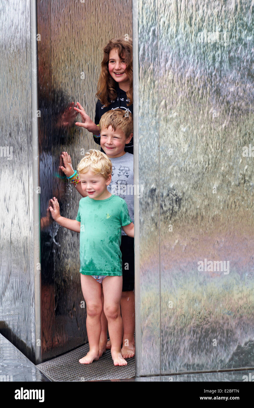 Genießen Sie das Wasser, stoppen drei Kinder, um posieren für ein Foto im Springbrunnen am Millenium Square, Harbourside, Bristol Stockfoto