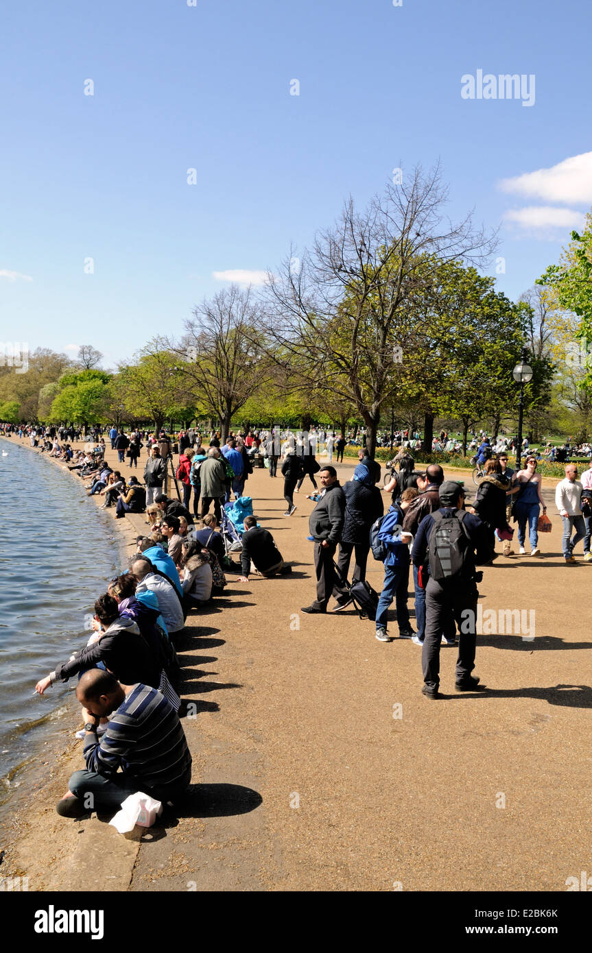 Leute sitzen an der Seite der Serpentine im Hyde Park London England Großbritannien UK Stockfoto