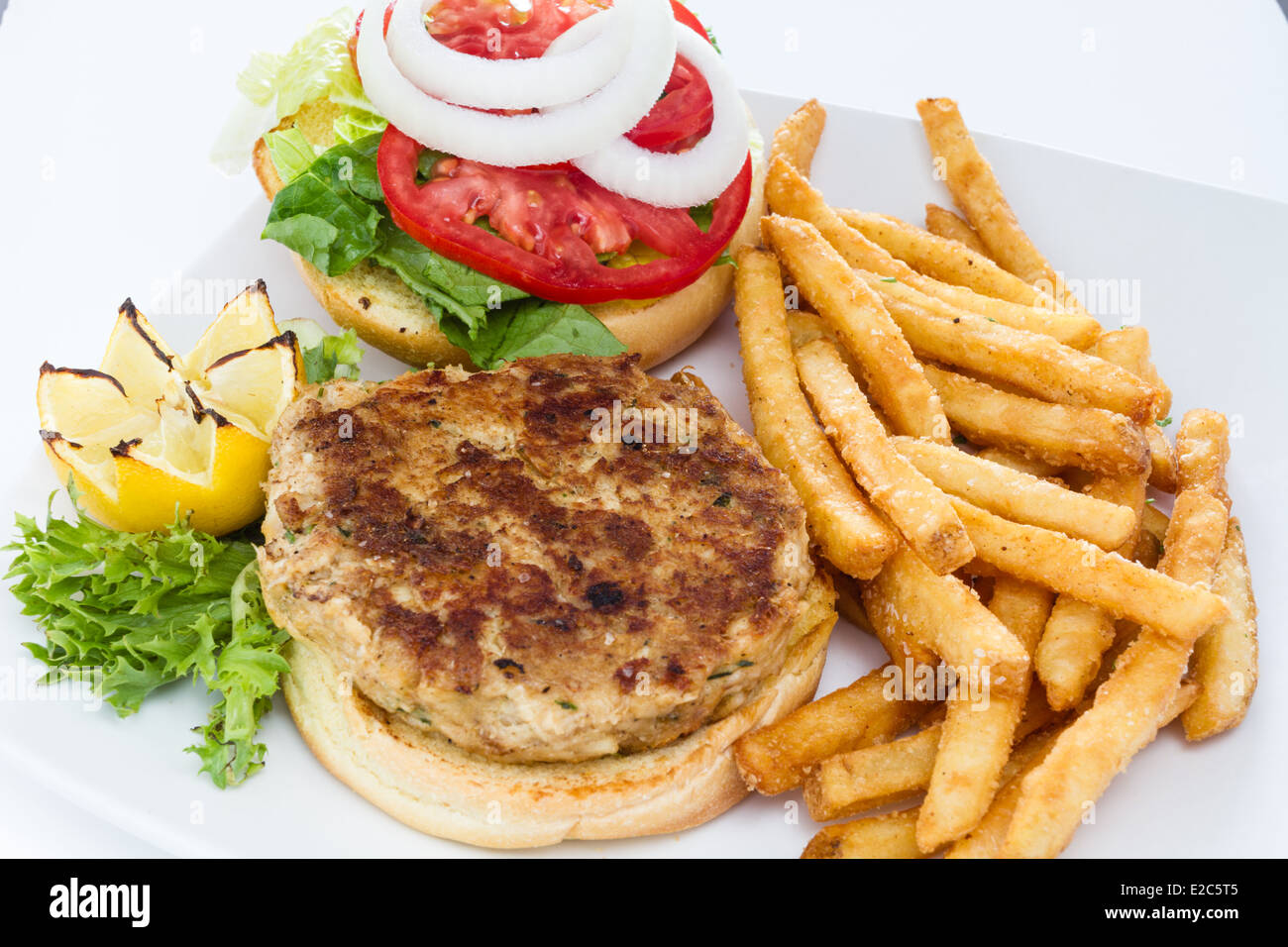 Pfanne gebraten Krabbe Kuchen Sandwich serviert mit einer Seitenlänge von Pommes Frites. Stockfoto