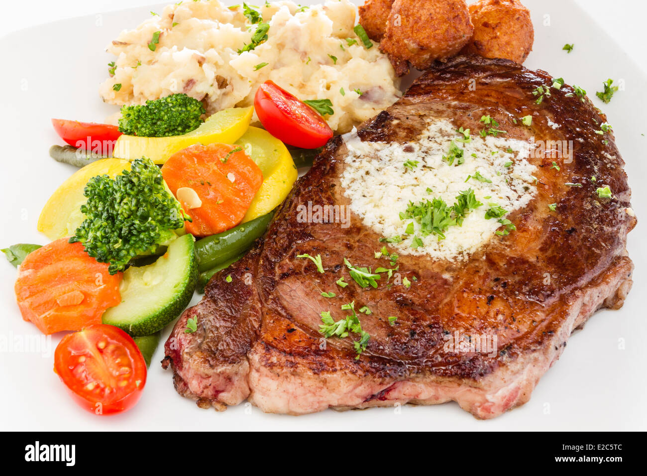 Ribeye Steak serviert mit Kartoffelpüree und Gemüse Medley Hush Welpen. Stockfoto