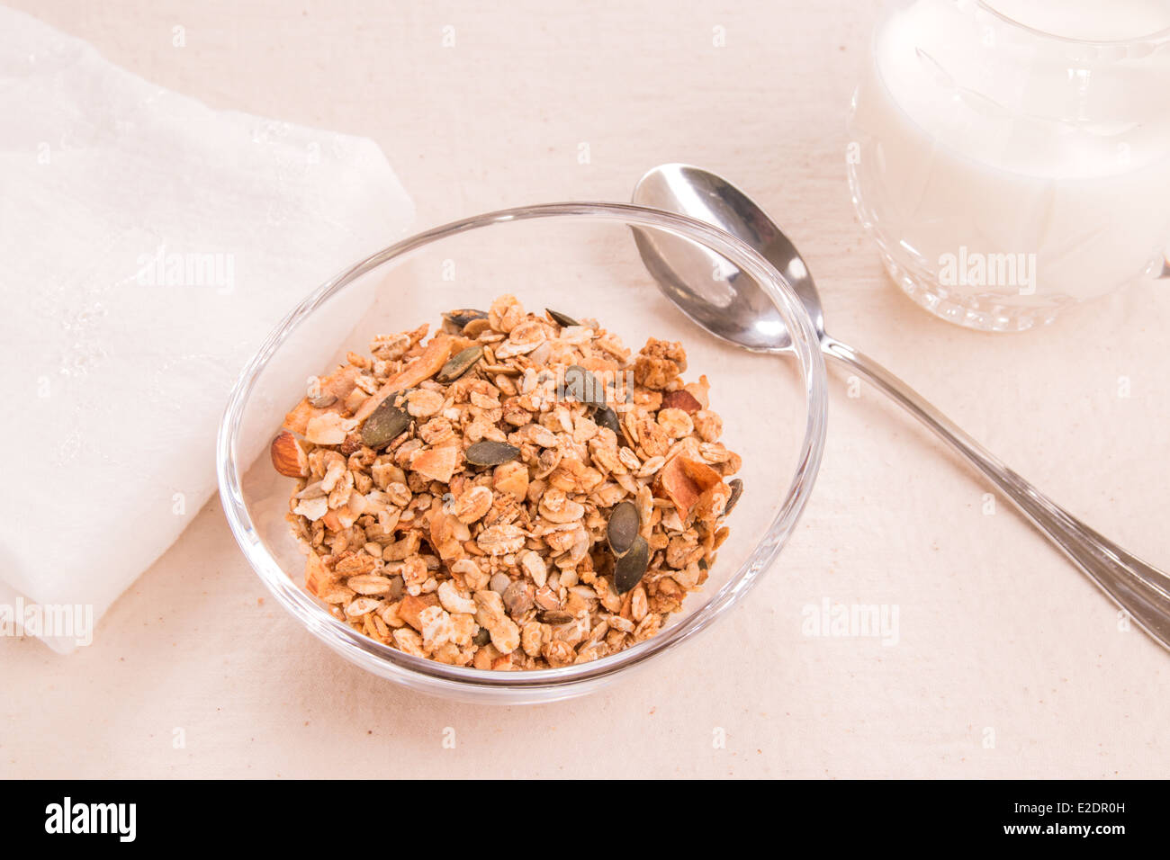 Müsli in einer Runde Schale auf einem cremefarbenen Tuch mit Löffel und Milch Krug (7 von 15) Stockfoto