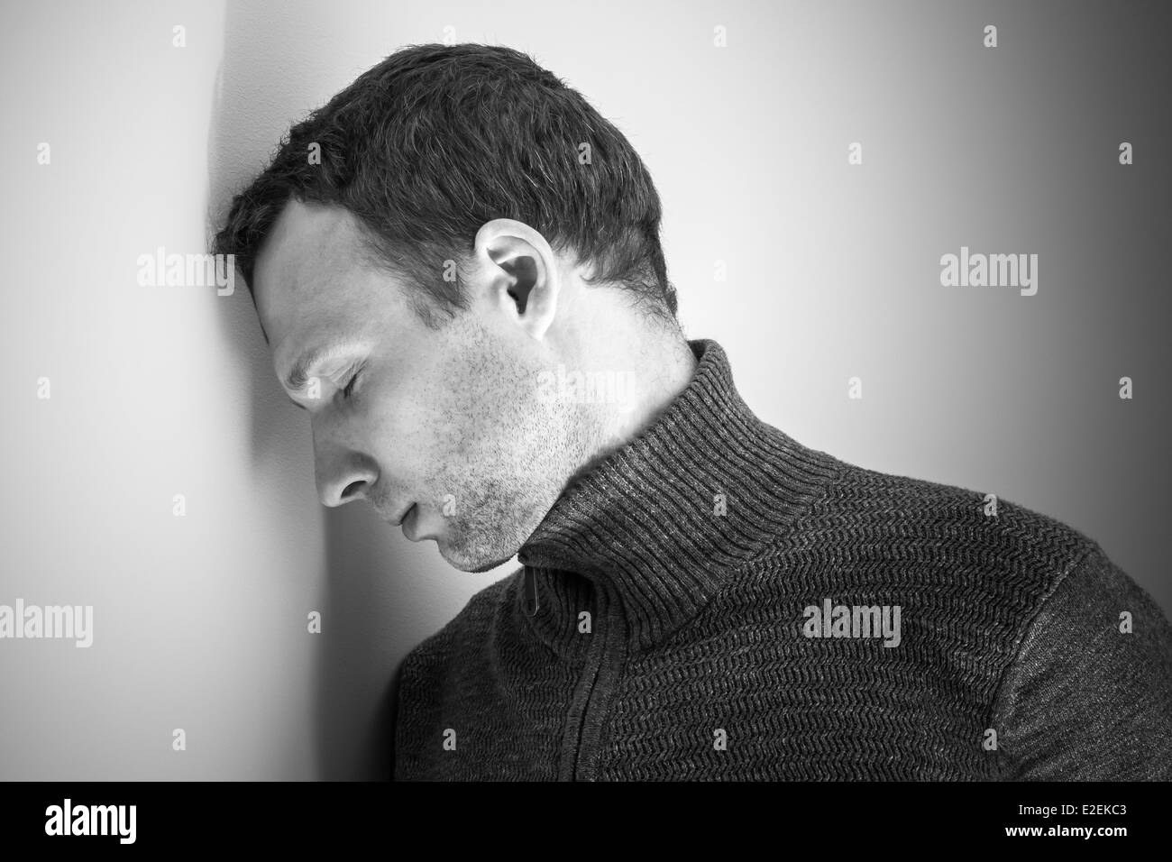 Traurige junge kaukasischen Mann und weiße Wand Stockfoto
