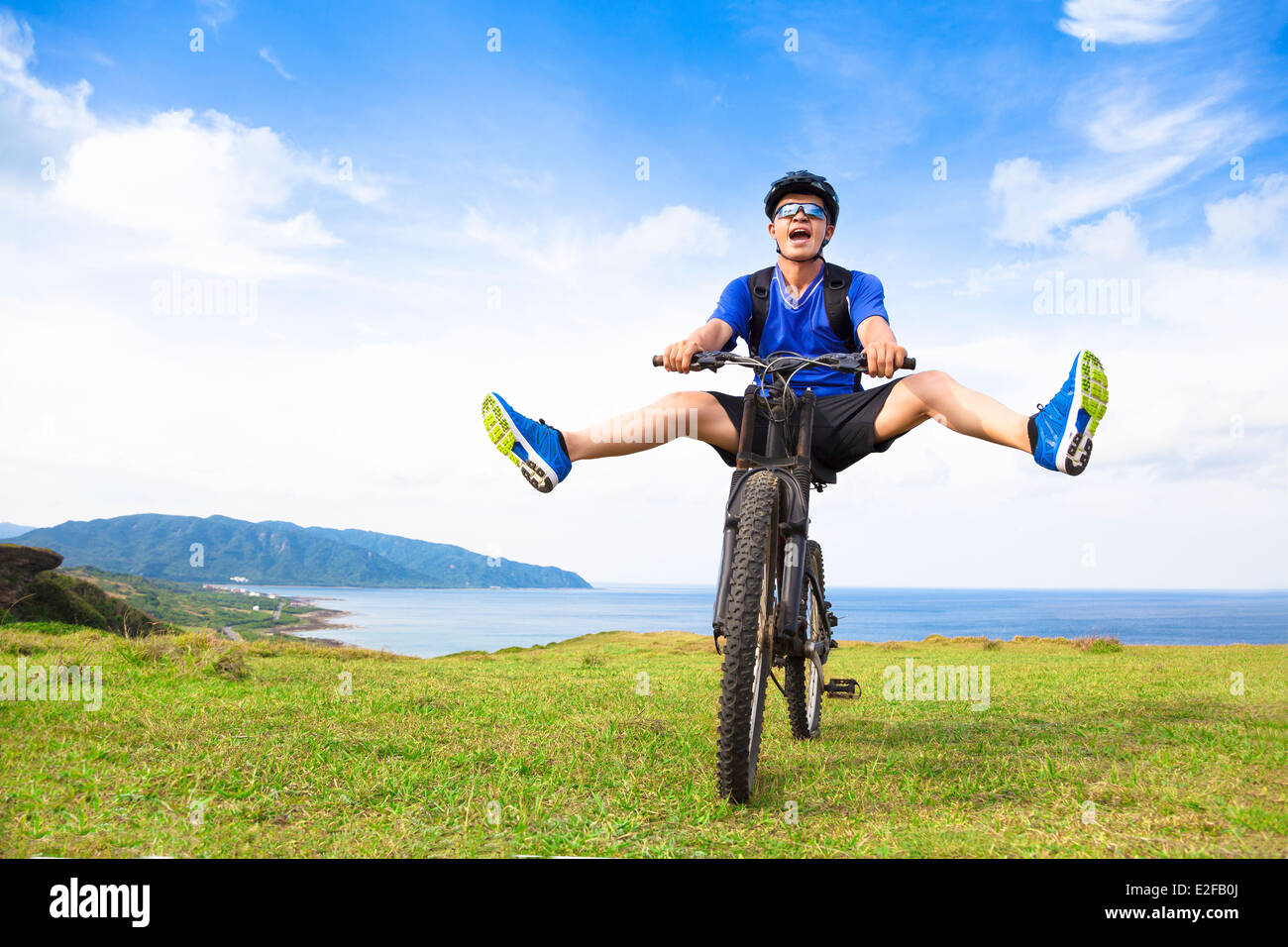 lustige junge Backpacker, die mit dem Fahrrad auf einer Wiese Stockfoto