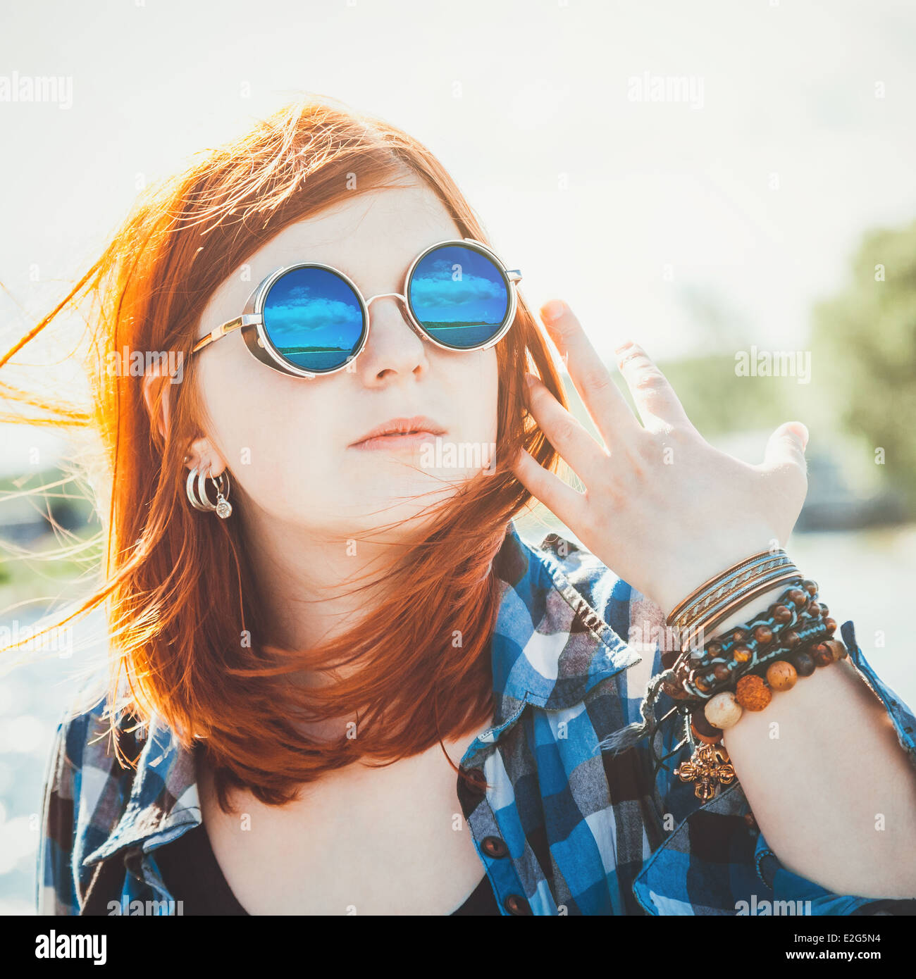 unbeschwerte, schöne junge Frau in Sonnenbrille mit Reflexion über Seestück Stockfoto
