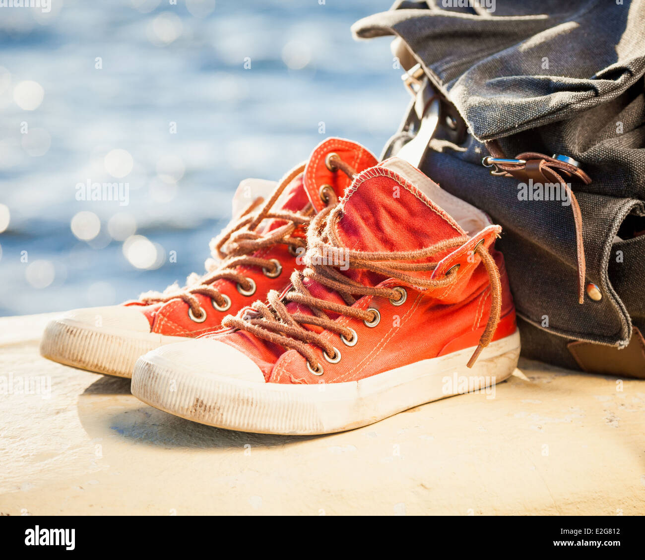 rote Turnschuhe und Rucksack auf Seelandschaft Stockfoto