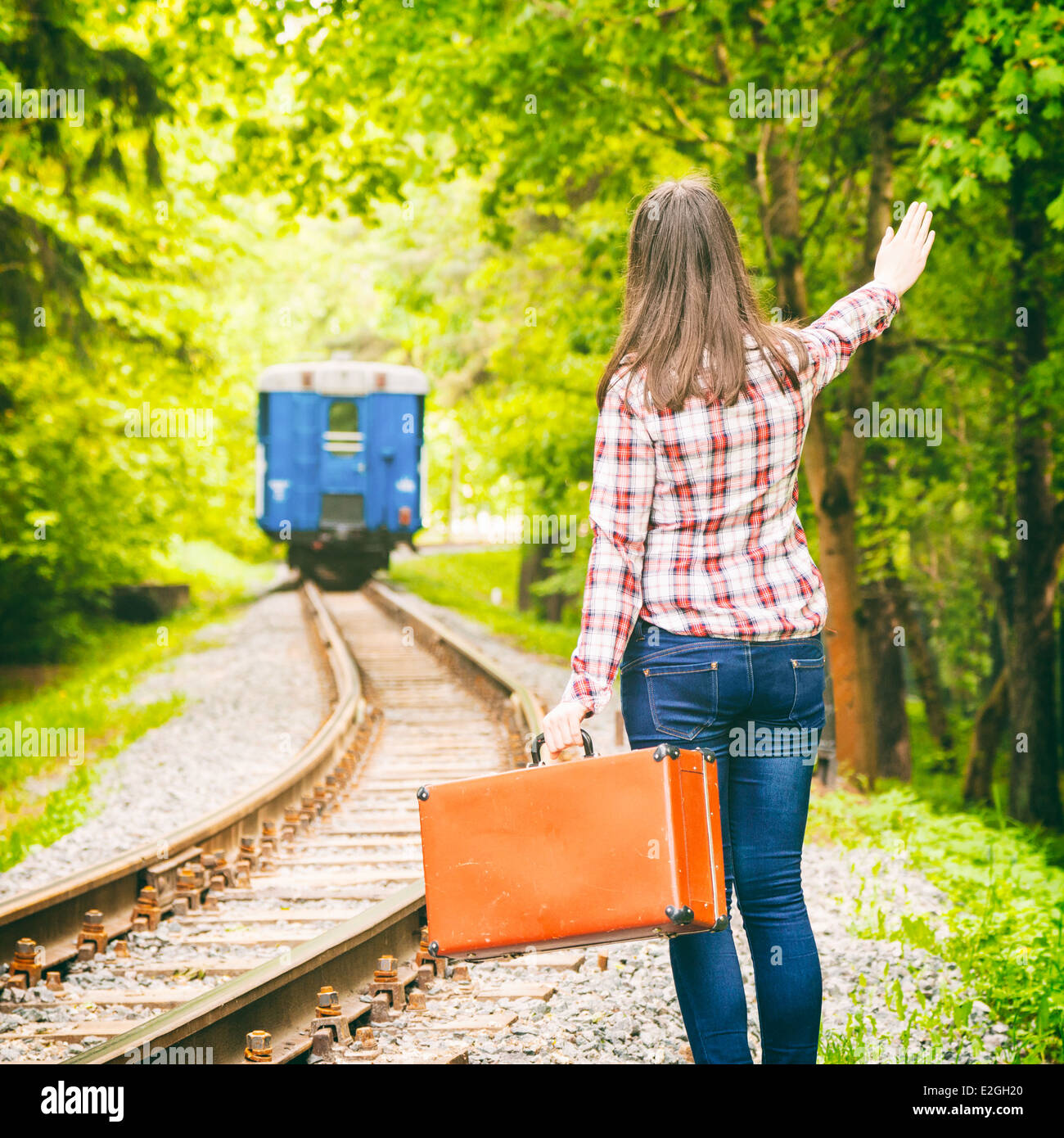 junge Frau mit alten Koffer seine Hand winken Abfahrt Zug auf Hintergrund Stockfoto