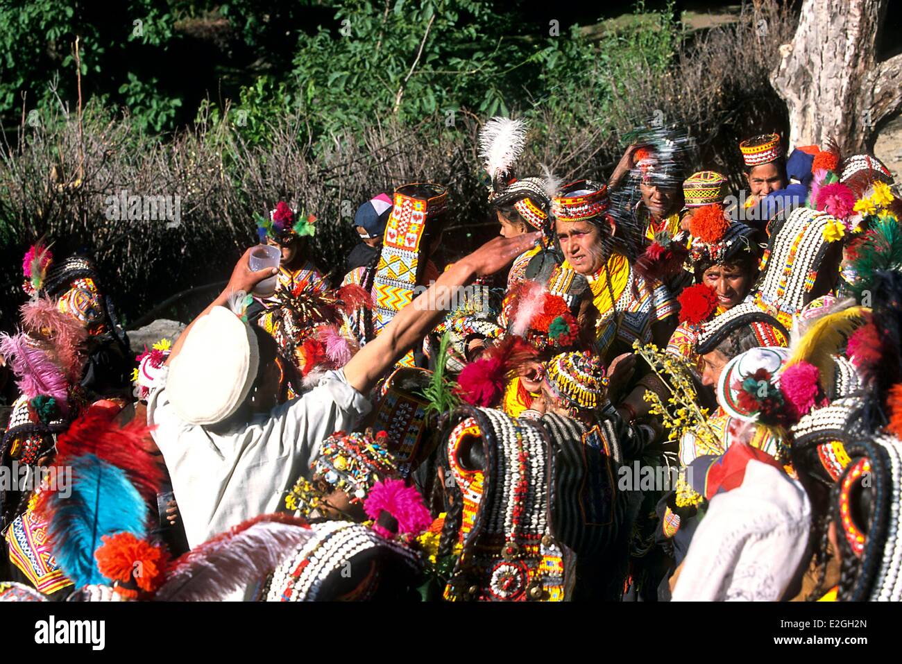 Pakistan Khyber Pakhtunkhwa Kalash Täler Bumburet Tal Kalash Frauen mit ihrem Baby im Arm versammeln sich um Officiant, die ihnen Milch während Ritual der neuen Kinder Suri Prao Licht in der Dämmerung Ritus zur Eröffnungsfeier des Joshi Frühlings Fülle besprengt Stockfoto