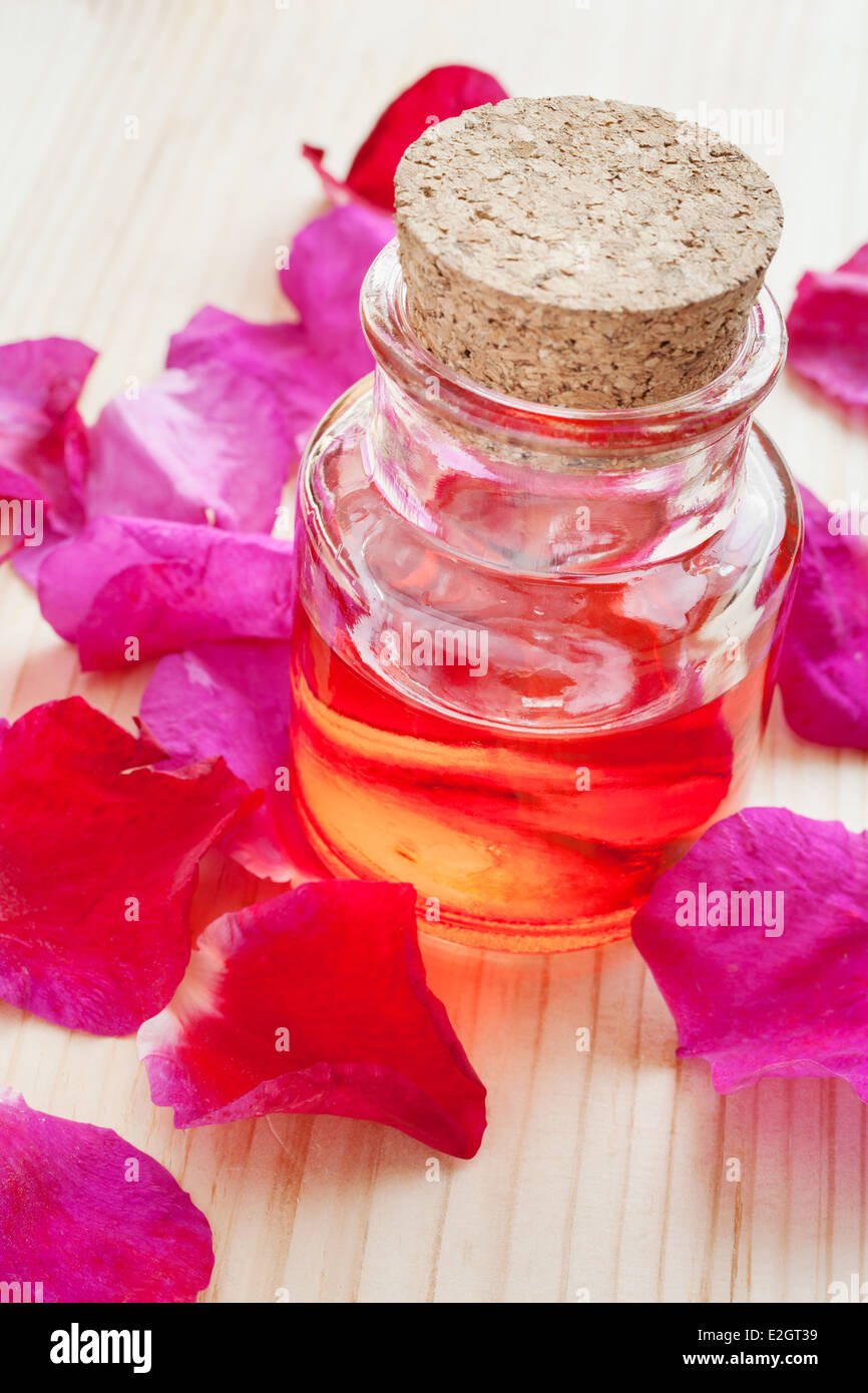 ätherisches Öl in Glasflasche und Rosenblüten Stockfoto