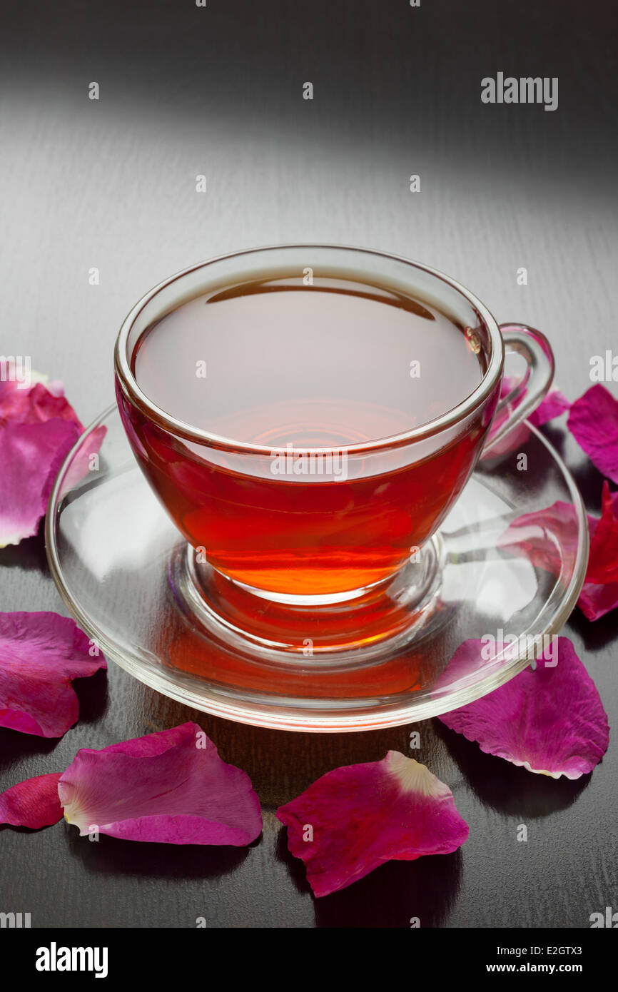 Kräutertee mit Rosenblättern auf dunklen Tisch Stockfoto