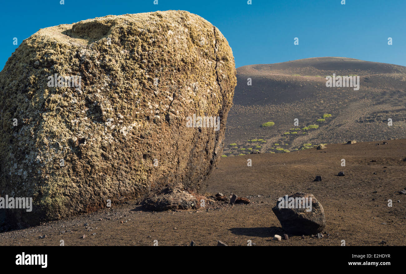 Riesige Basalt vulkanische Bombe aus eine explosive Eruption des Montaña Colorada, Lanzarote, mit nahe gelegenen Montañs Negra im Hintergrund Stockfoto
