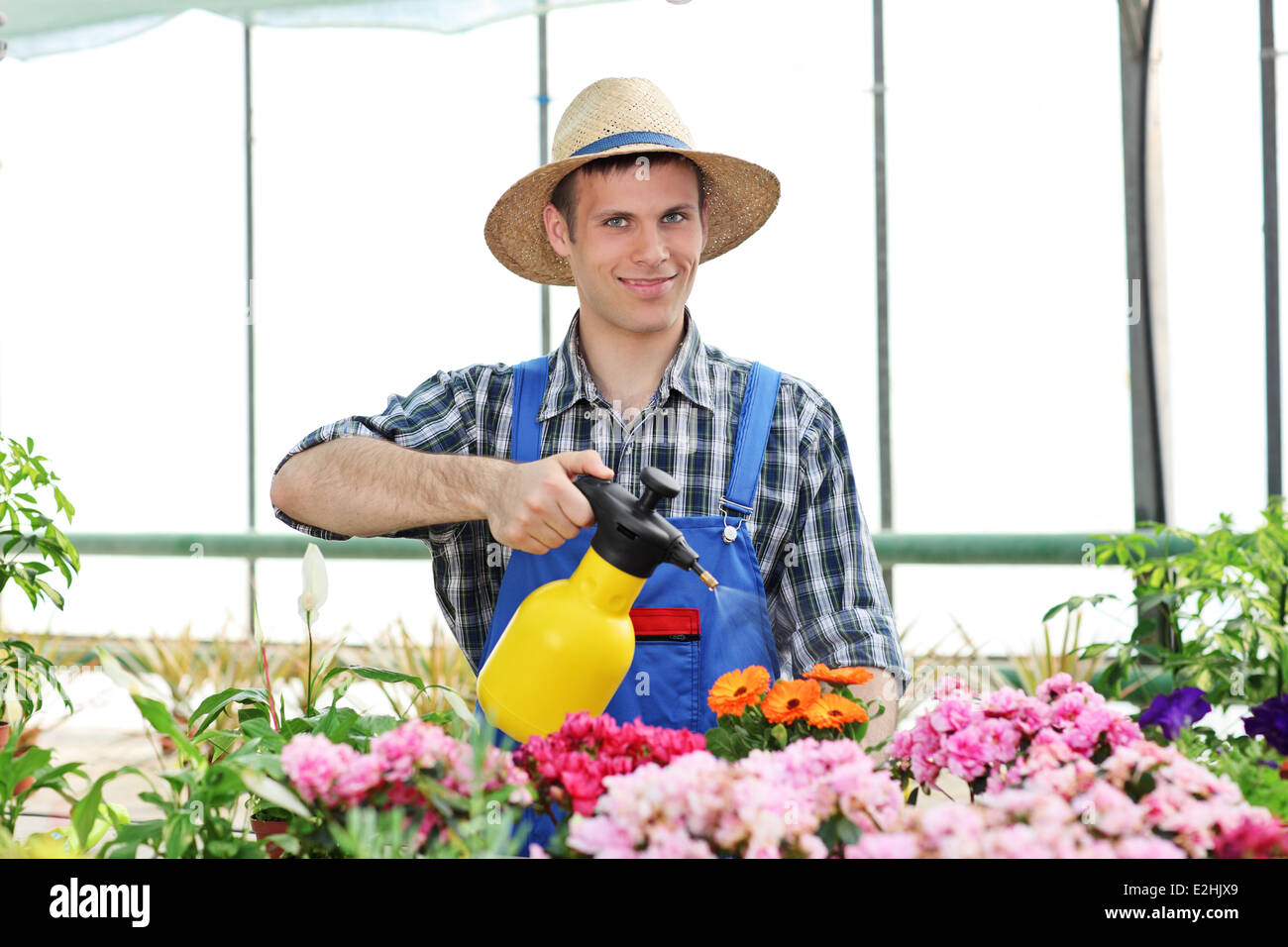 Männliche Gärtner Blumen in einem Garten mit einer Gießkanne gießen