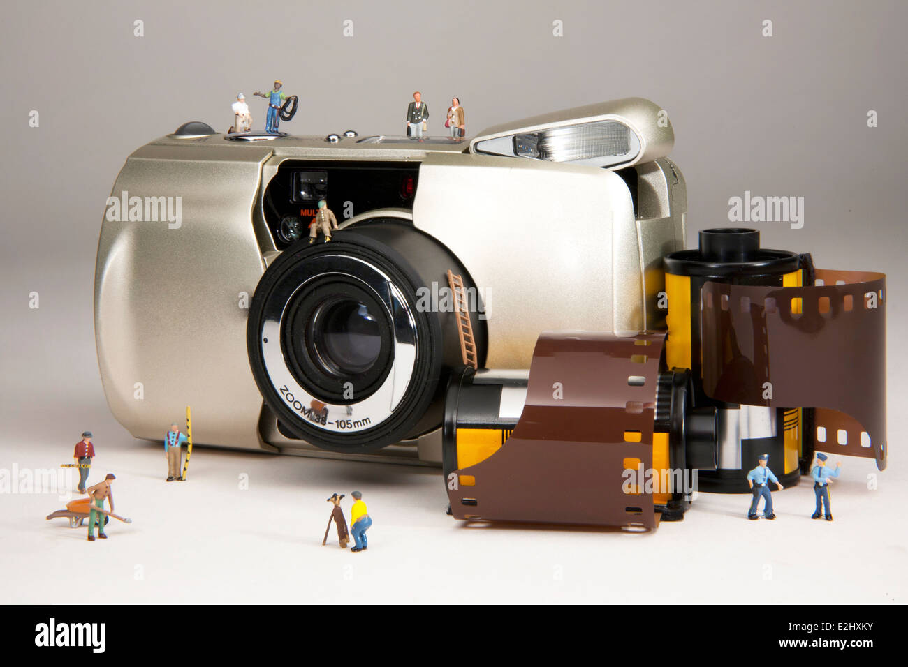 Miniatur-Menschen mit einem 35mm film Kamera und film Rollen das Bild komponieren. Stockfoto