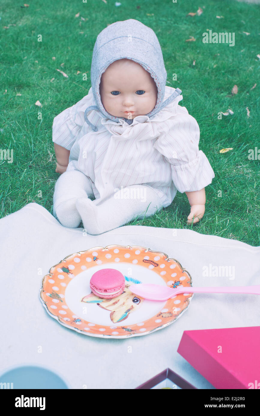 Baby-Puppe sitzt auf der Picknickdecke Stockfoto
