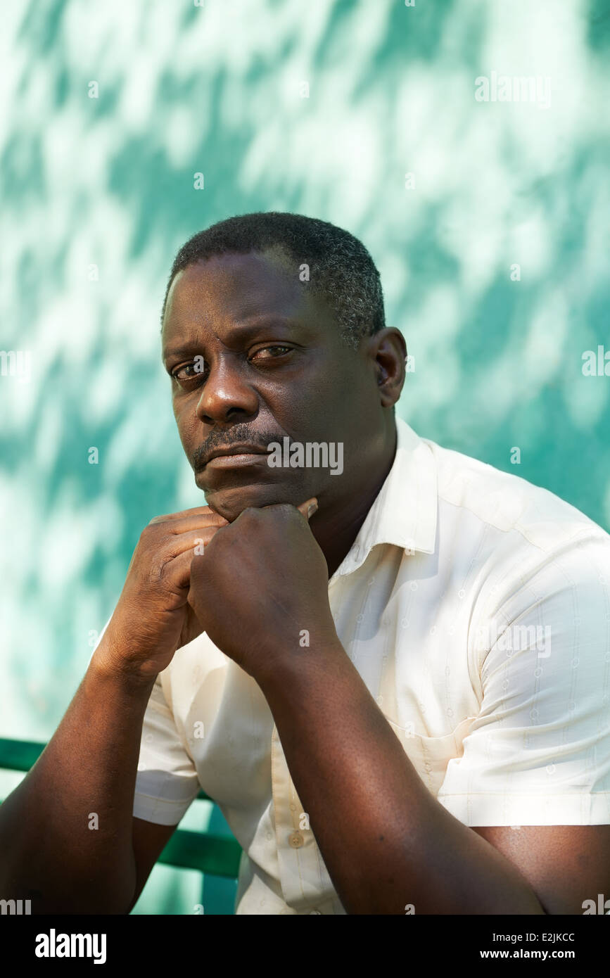 Porträt von Mitte afroamerikanische Mann mit Hand am Kinn, im Park sitzen und Blick in die Kamera mit traurigen Ausdruck Stockfoto