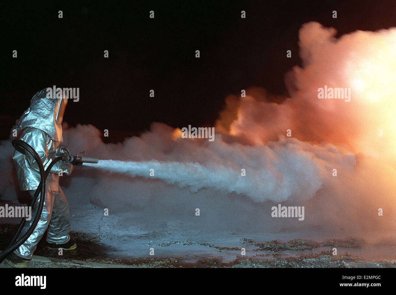 Senior Airman Nähe Anzug verwendet einen Schlauch auf um eine trockene chemische Feuer Suppressant während einer Übung zur Brandbekämpfung zu verzichten. Stockfoto