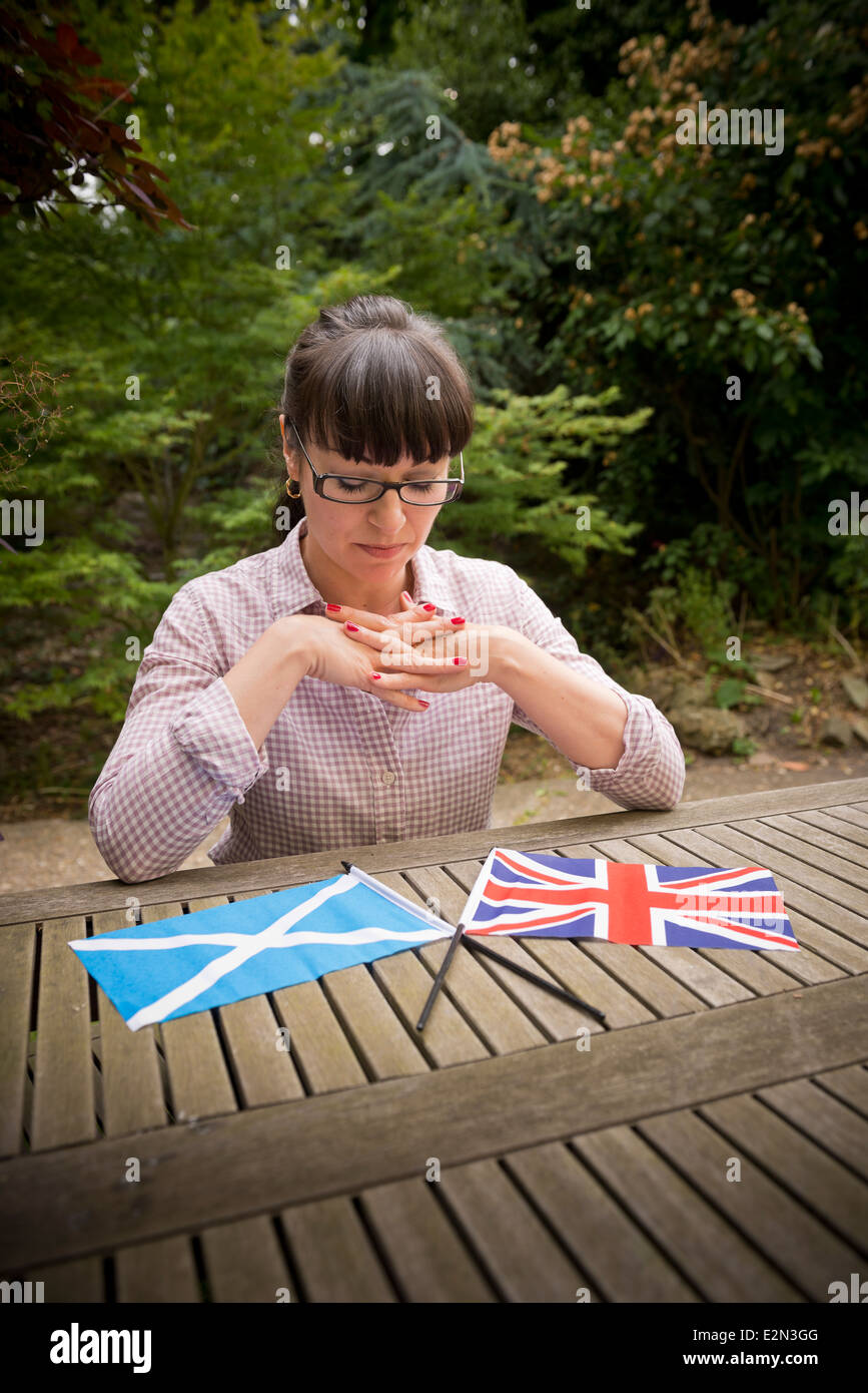 Junge Frau betrachten eine schottische und britische Flagge, die entscheiden, wie Sie in die schottische Unabhängigkeitsreferendum abstimmen Stockfoto