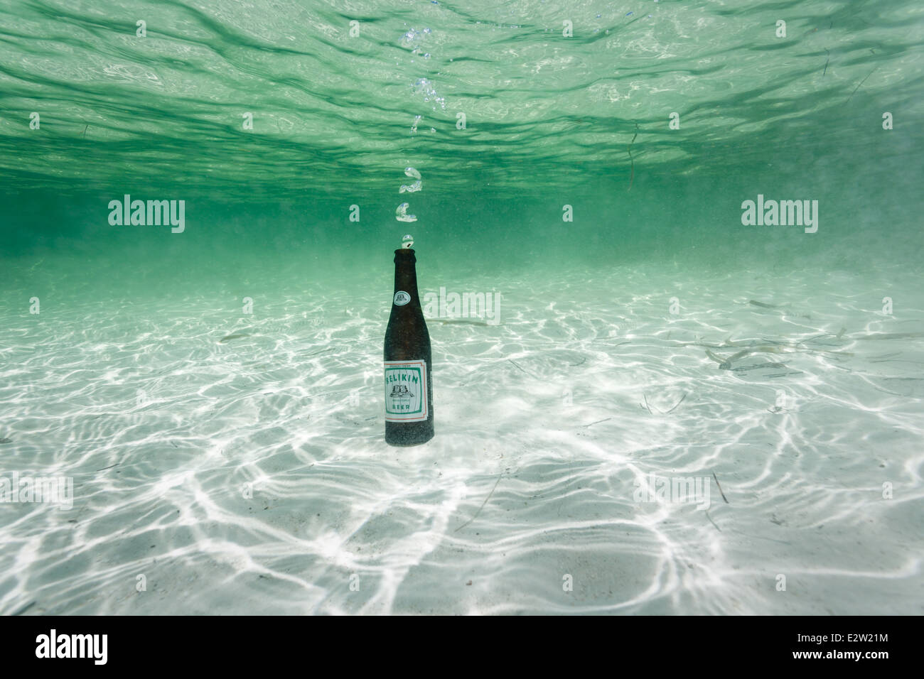 Belikin Bierflasche auf weißem Sand auf Unterseite des klare türkisblaue Meer bläst Seifenblasen beim Einfüllen des Wassers Stockfoto