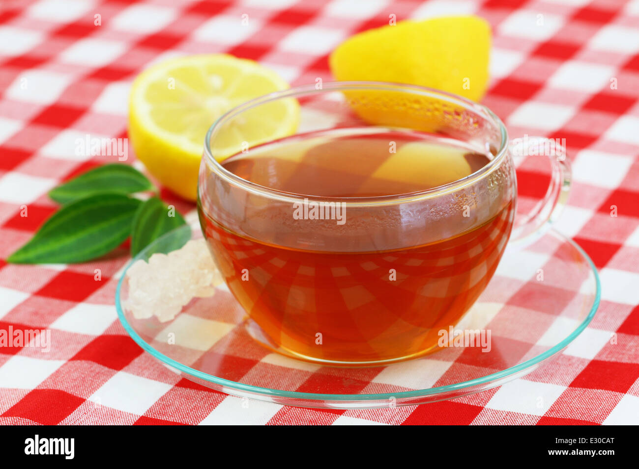 Tasse Tee und Zitrone auf kariertem Stoff Stockfoto