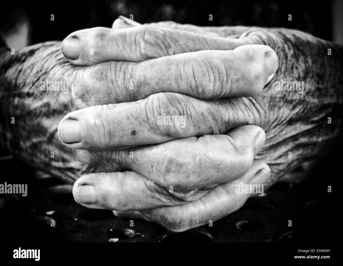 Sehr alte Frau hält ihre Hände zusammen, schwarz und weiß. Selektiven Fokus in der Mitte der Hände Stockfoto